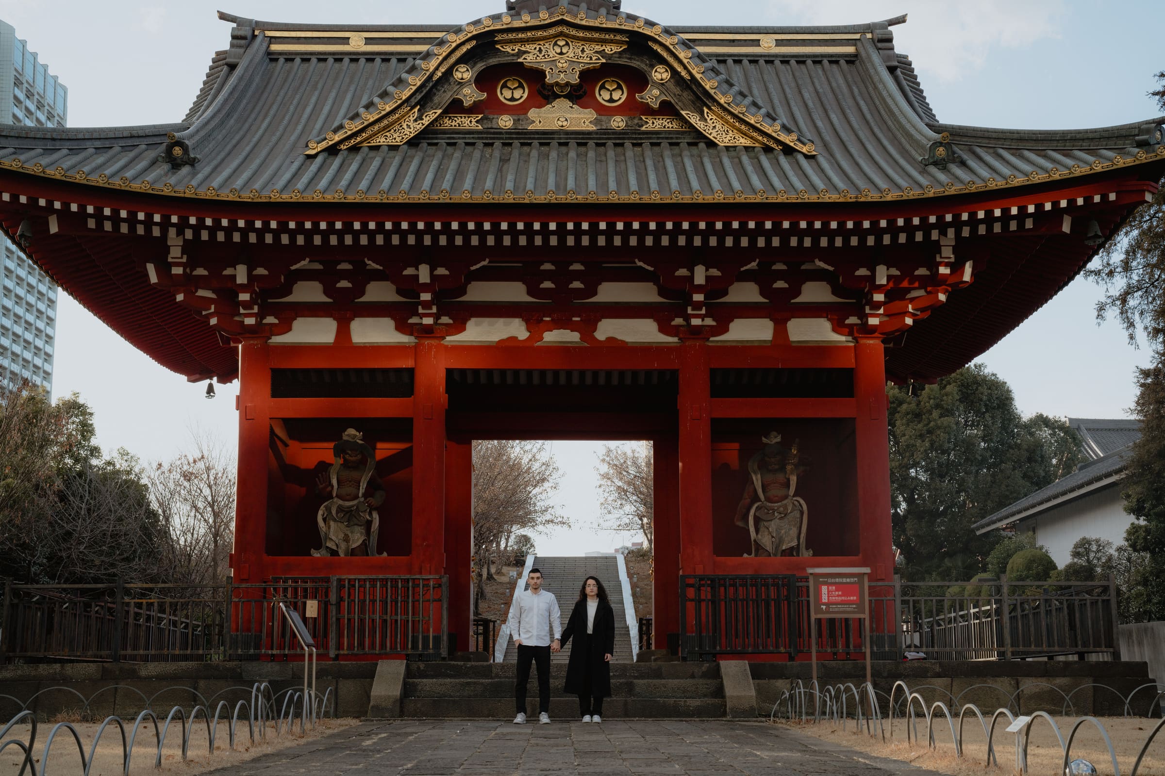Julia e Luiz de mãos dadas sob um portão de templo japonês vermelho, em Tóquio